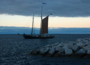 The grace of a sailboat against the dimming glow of dusk reflects the tranquility of a journey at sea.