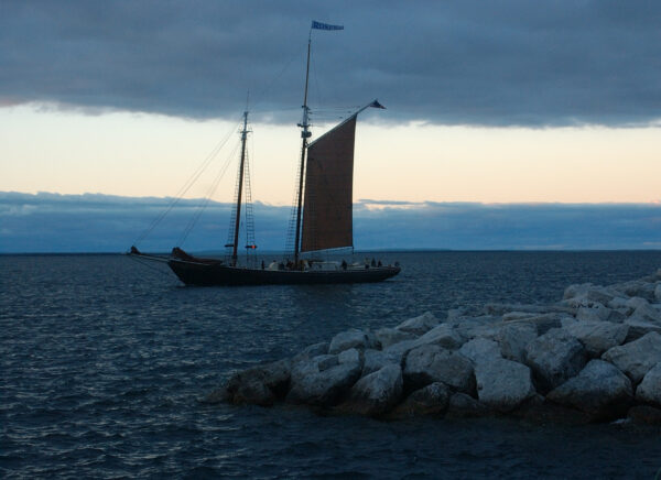 The grace of a sailboat against the dimming glow of dusk reflects the tranquility of a journey at sea.