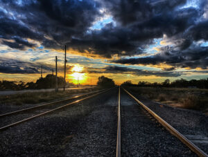 Dramatic clouds and a stunning sunset over railway tracks, symbolizing the journey's continuity