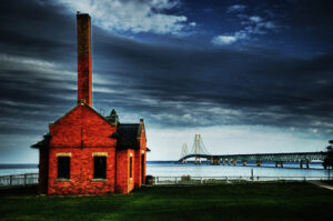 Red brick structure with the Mackinac Bridge in the background under a dramatic sky.