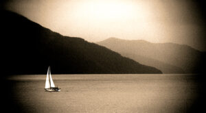 Solitude at Dusk - A Lone Sailboat Against Alaskan Mountains