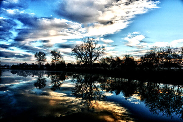 Vibrant dawn sky and tree reflections on Bessie's Creek in a photograph by Ken Osborne.