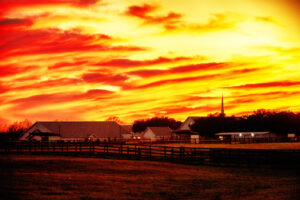 Fiery clouds at sunrise over a rural farm and church, captured by Ken Osborne.