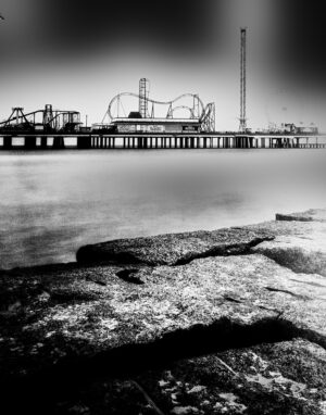 Infrared photograph of an empty amusement park on the pier with rides and attractions standing still.