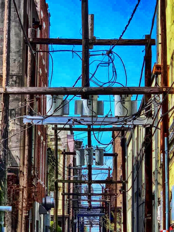 A vibrant and complex mesh of electrical wires in Galveston’s alley, symbolizing urban energy.