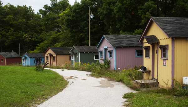 A row of colorful hunting lodges along a curved pathway, symbolizing peaceful rural life