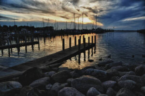 Tranquil Michigan harbor at dusk with still waters and moored sailboats under a cloud-streaked sky