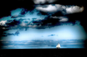 A lone sailboat navigating the expansive blue ocean under a cloud-filled sky