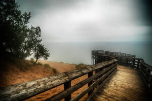 A misty overcast view from Sleeping Bear Dunes' boardwalk overlooking the calm waters