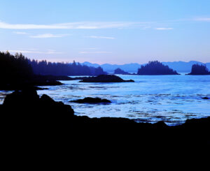 Serene sunrise over the Canadian shoreline with silhouettes of islands against a blue dawn sky.