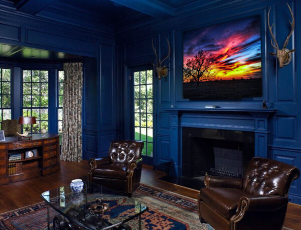 "Twilight Blaze" photograph by Ken Osborne displayed above the fireplace in a sophisticated living room