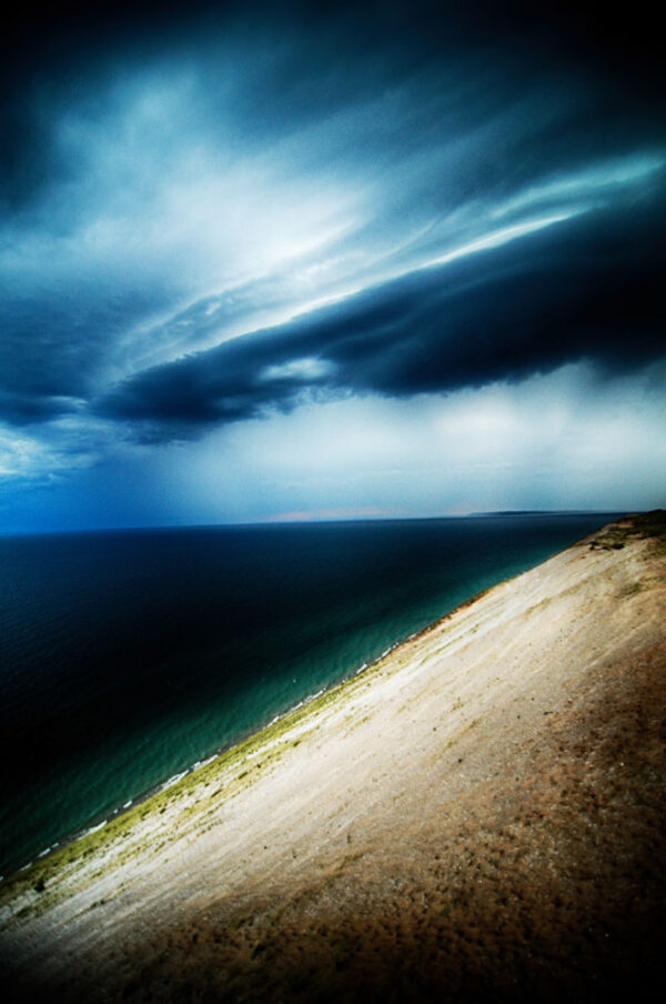 Dramatic storm clouds looming over the serene Sleeping Bear Dunes, captured by Ken Osborne