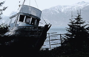 Abandoned fishing boat with a backdrop of Alaskan mountains