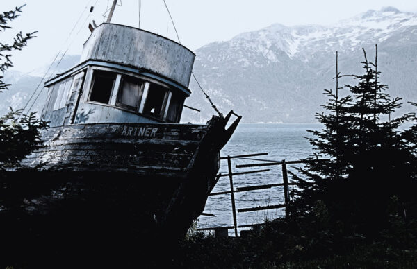 Abandoned fishing boat with a backdrop of Alaskan mountains