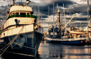 Alaskan fishing boats docked in the harbor with sun setting in the background