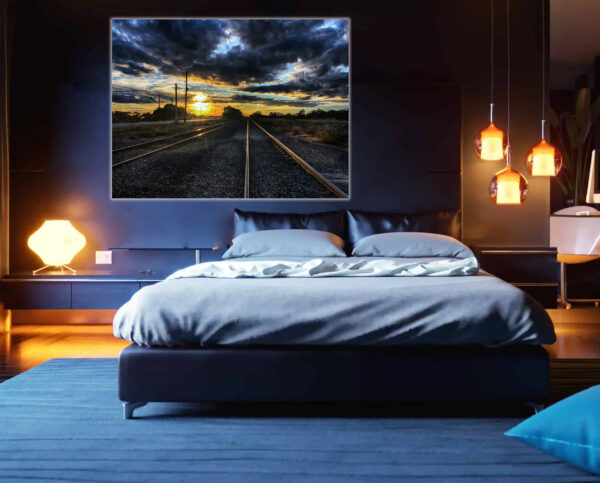 "Sunset Tracks" - A dramatic landscape photograph of railway tracks leading into a vivid sunset, mounted on the wall of a modern bedroom.